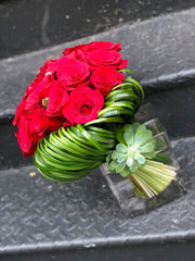 A Bouquet Style Rose Arrangement with Accents of Green Modern Leaf work and a succulent.