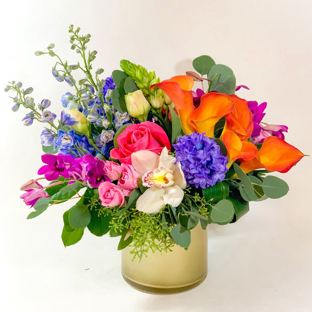 Flowers include delphinium, roses, orchids, hyacinth, calla lily, and mixed greenery.