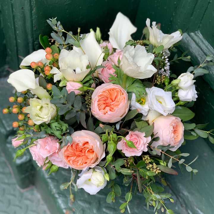 blend of peach garden roses, blush spray roses, white anemone , peach hypericum berry, and mixed eucalyptus