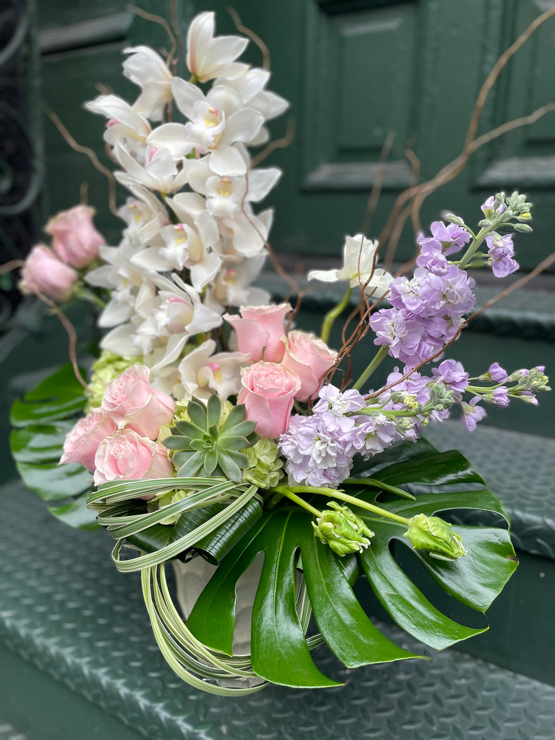 Dramatic Orchid and Rose display in a tall gold specialty vase.