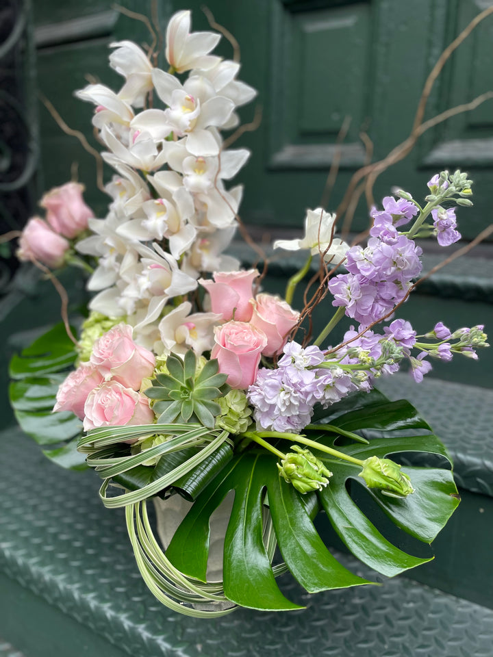 Dramatic Orchid and Rose display in a tall gold specialty vase.