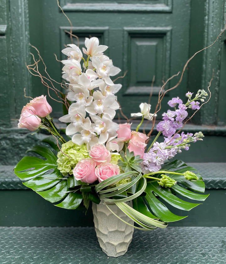 Dramatic Orchid and Rose display in a tall gold specialty vase.