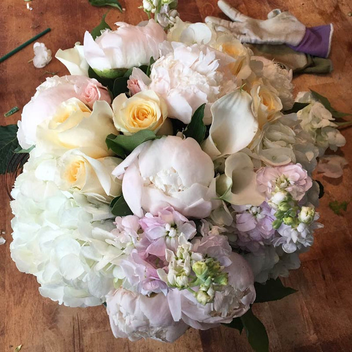 A blend of pastels in blush, light yellow, creams, and whites. Includes a variety of Roses, Peony, Stock, Hydrangea, and Calla.