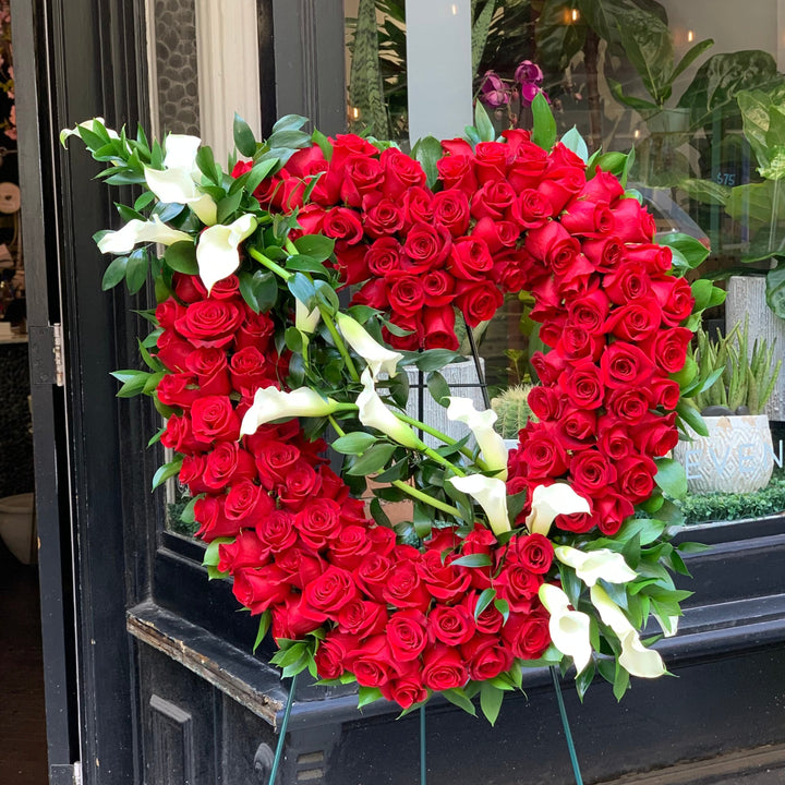 Luxurious Red Roses designed in an Open Heart with White Calla Lillies.
