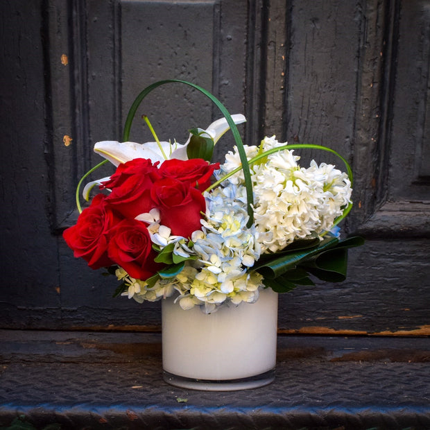 red roses, blue hydrangea, and white hyacinth, lilies, and tulips