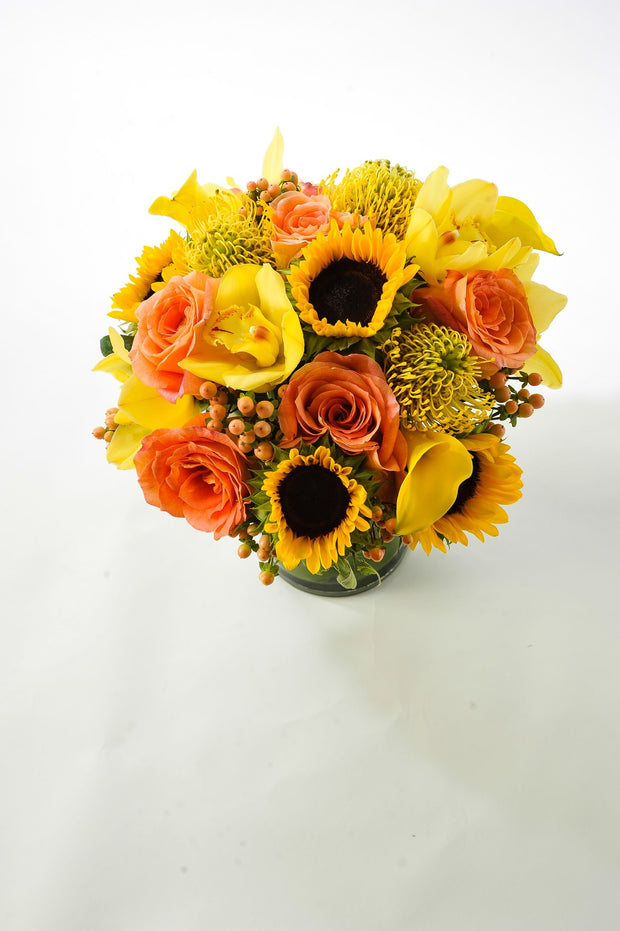  sunflowers, yellow orchids, protea, and tropicals with accents of berries