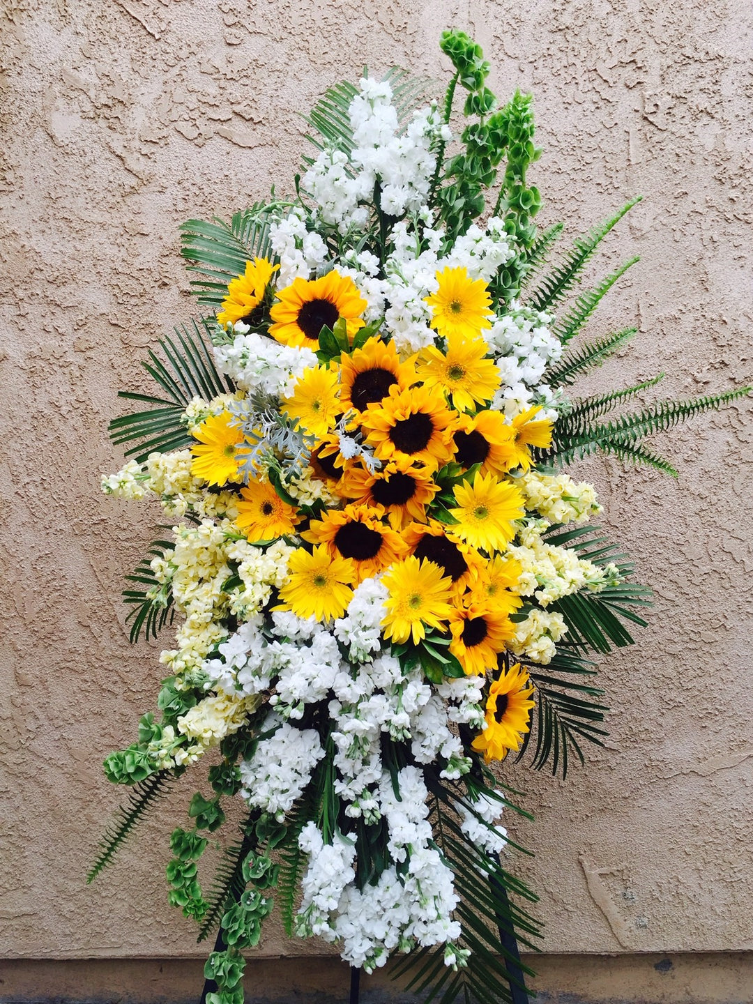 standing spray sunflowers, gerbera daisies, fragrant stock, and bells of Ireland